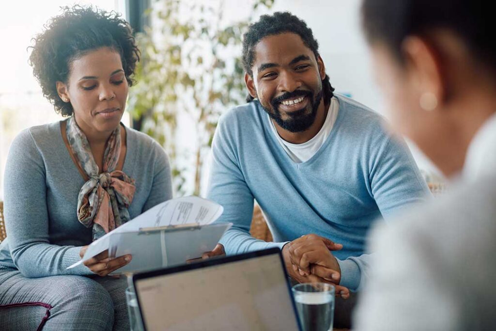 Adults review a life insurance denial letter and medical documents at a kitchen table.