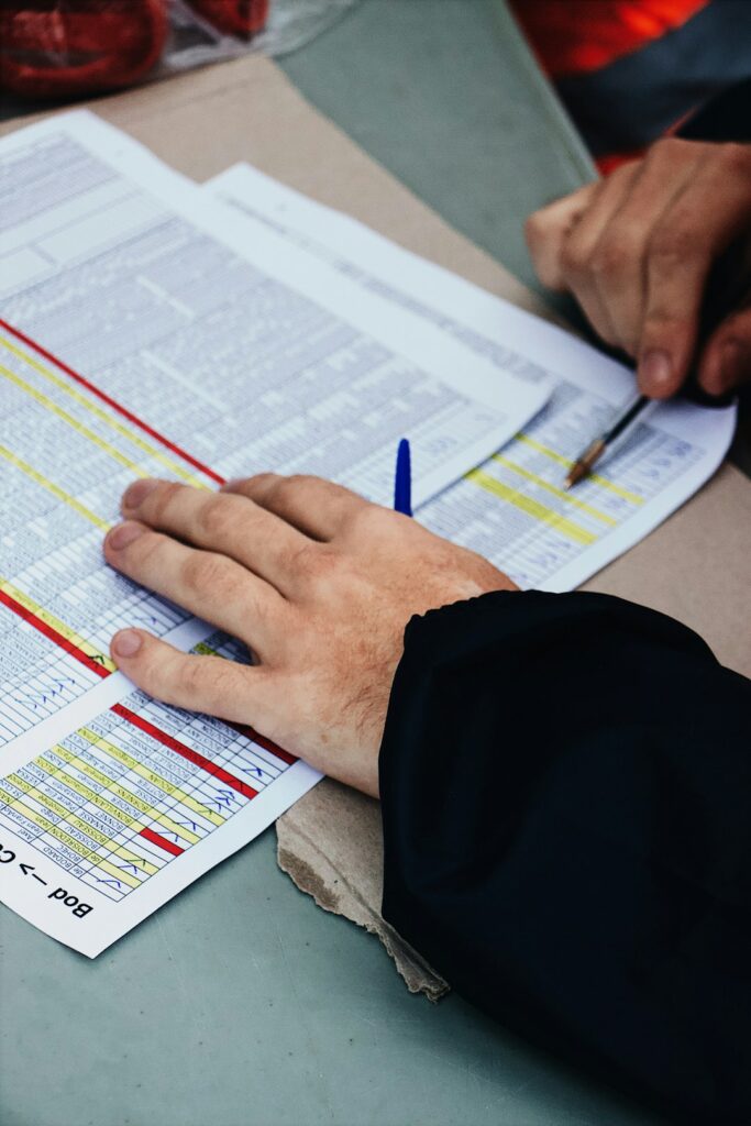 Person reviewing disability insurance documents beside medical records, a calculator, and household budget papers.